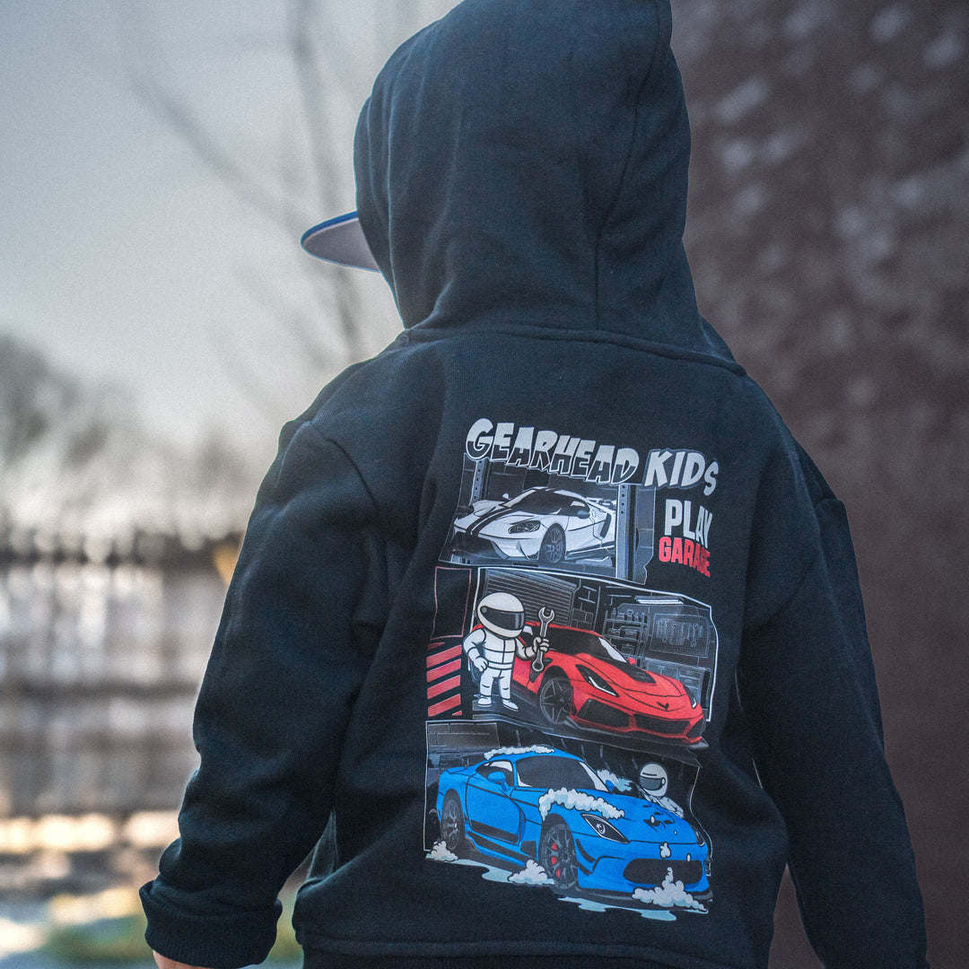 Little boy wearing a Gearhead Kids American Muscle Play Garage Hoodie featuring a white Ford GT, Red Corvette ZR1 and a Dodge Viper ACR