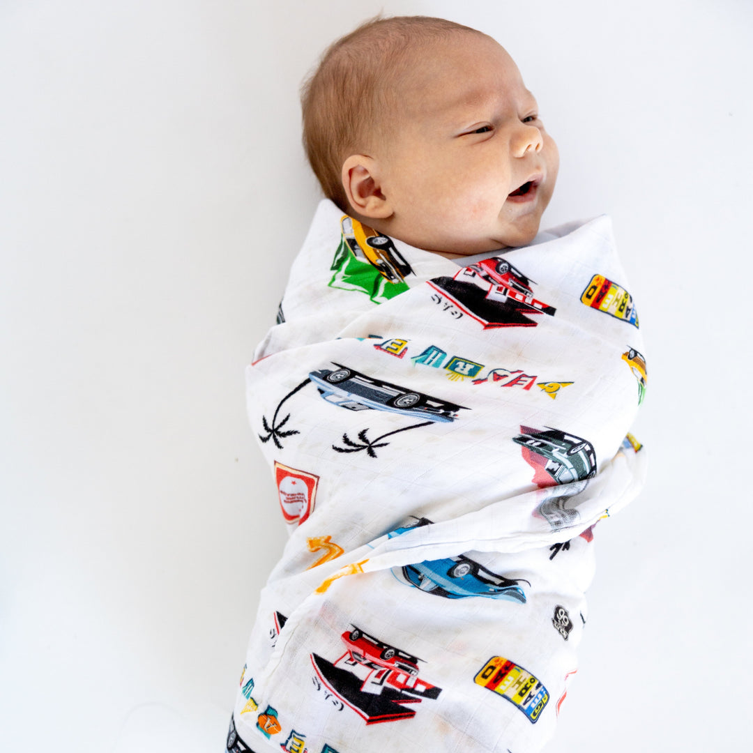 baby swaddled in the American Muscle Car bamboo muslin blanket featuring mustang fastback and camaro z28 - Gearhead Kids