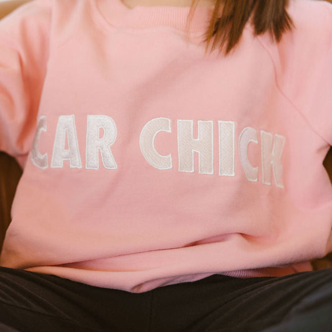 Close-up of high-density CAR CHICK embroidery on pink organic cotton fabric - Gearhead Kids