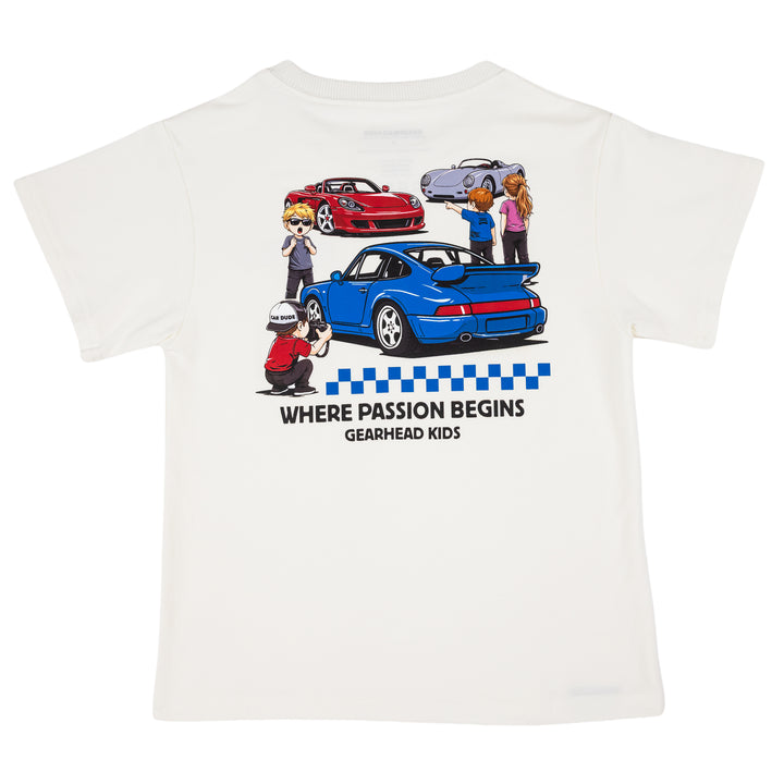 Off-white short-sleeve t-shirt featuring a 964 turbo sports car, silver 550 spyder and a red mid-engine supercar, with the text 'WHERE PASSION BEGINS GEARHEAD KIDS' printed below.