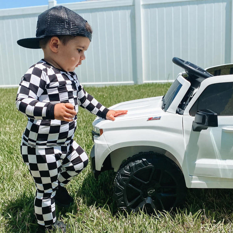 Toddler wearing checkered racing pajamas next to a white truck - Gearhead Kids