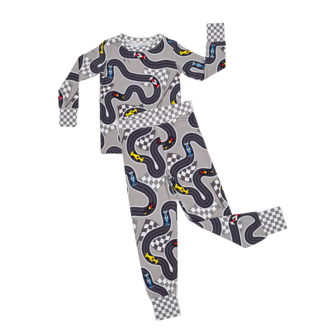 Flat Lay photograph of Circuit Dreamer Pajamas featuring F1 and Indy style race cars on a track on a white background  - Gearhead Kids