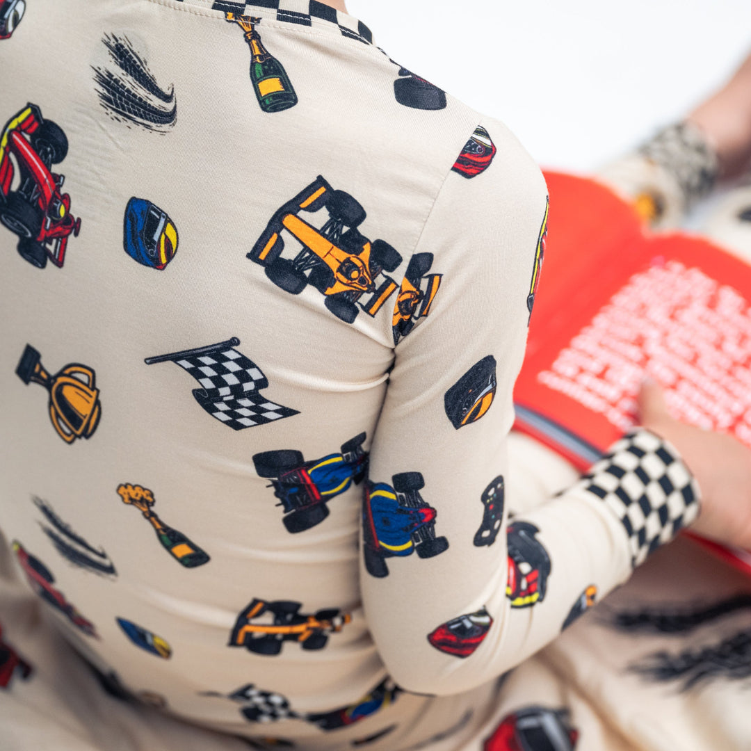Little kid wearing bamboo F1 themed pajamas reading the F1 Alphabet Legends book.  | Gearhead Kids 