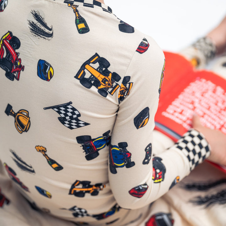 Little kid wearing bamboo F1 themed pajamas reading the F1 Alphabet Legends book.  | Gearhead Kids 