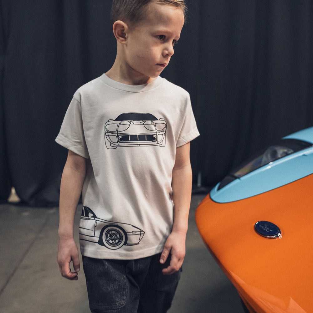 Boy wearing a Ford GT Outline T-shirt in Dust Color standing next to a 2005 Ford GT Car |  Gearhead Kids | Car Apparel for Kids