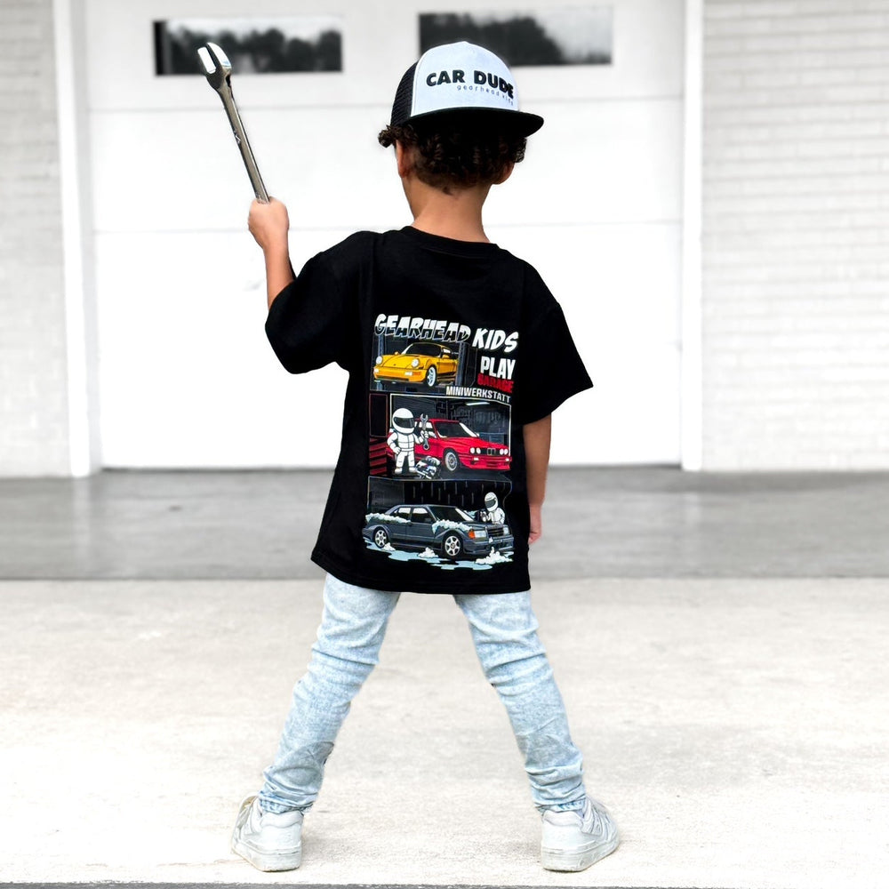 Toddler Boy wearing a Gearhead Kids Play Garage T-Shirt featuring BMW E30 M3, Mercedes 190E Evo II, and Porsche 911 Porsche 964.