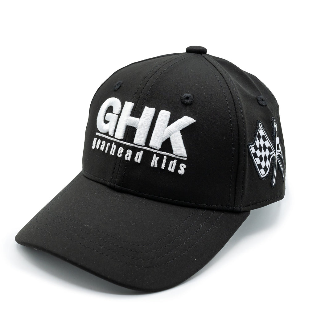 A black structured baseball cap with 'GHK Gearhead Kids' printed in white on the front and black and white checkered flags on the side