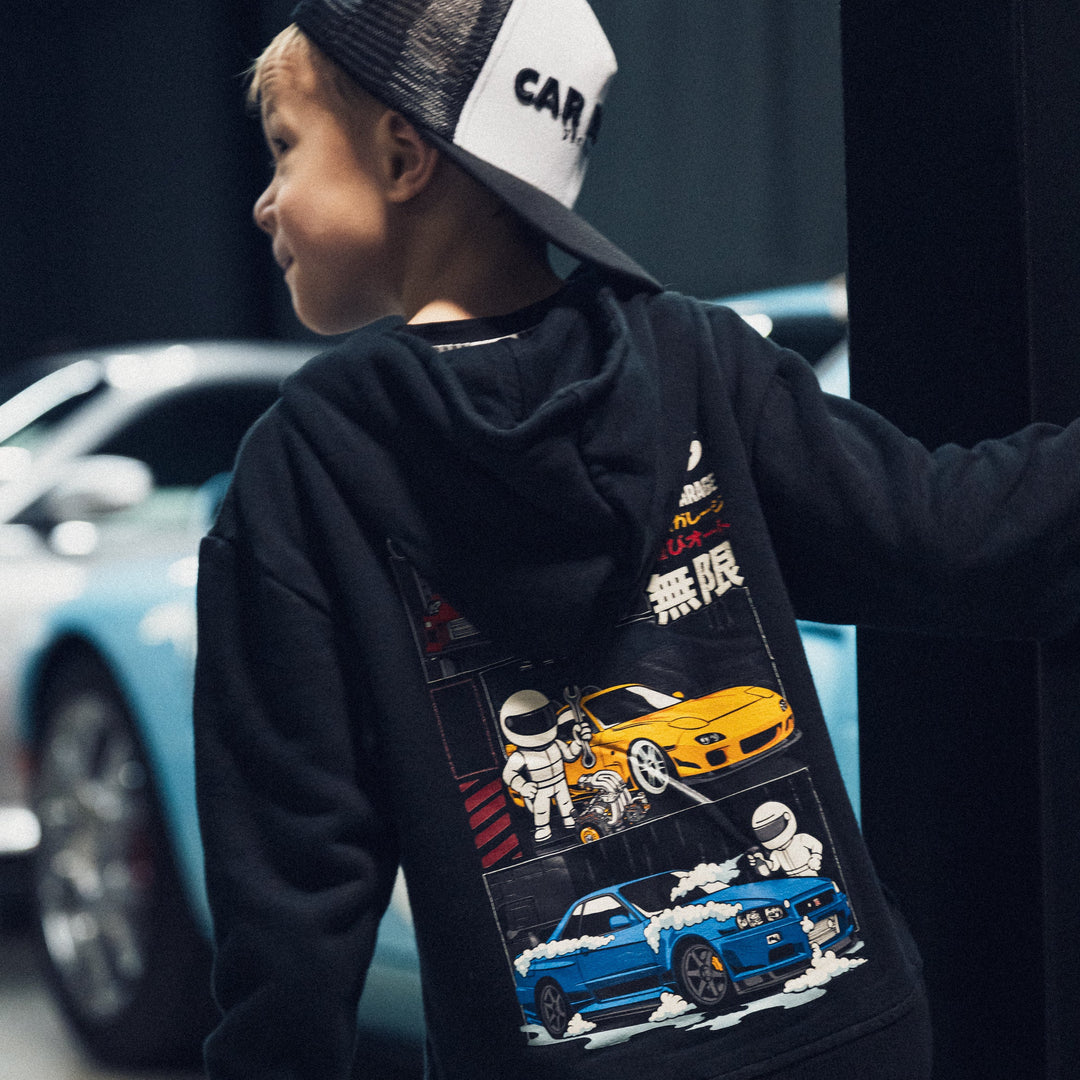 Little boy wearing a black Play Garage Hoodie with a red Toyota Supra, Yellow Mazda RX7 and Blue Nissan GTR R34 - Gearhead Kids apparel for automotive Enthusiasts