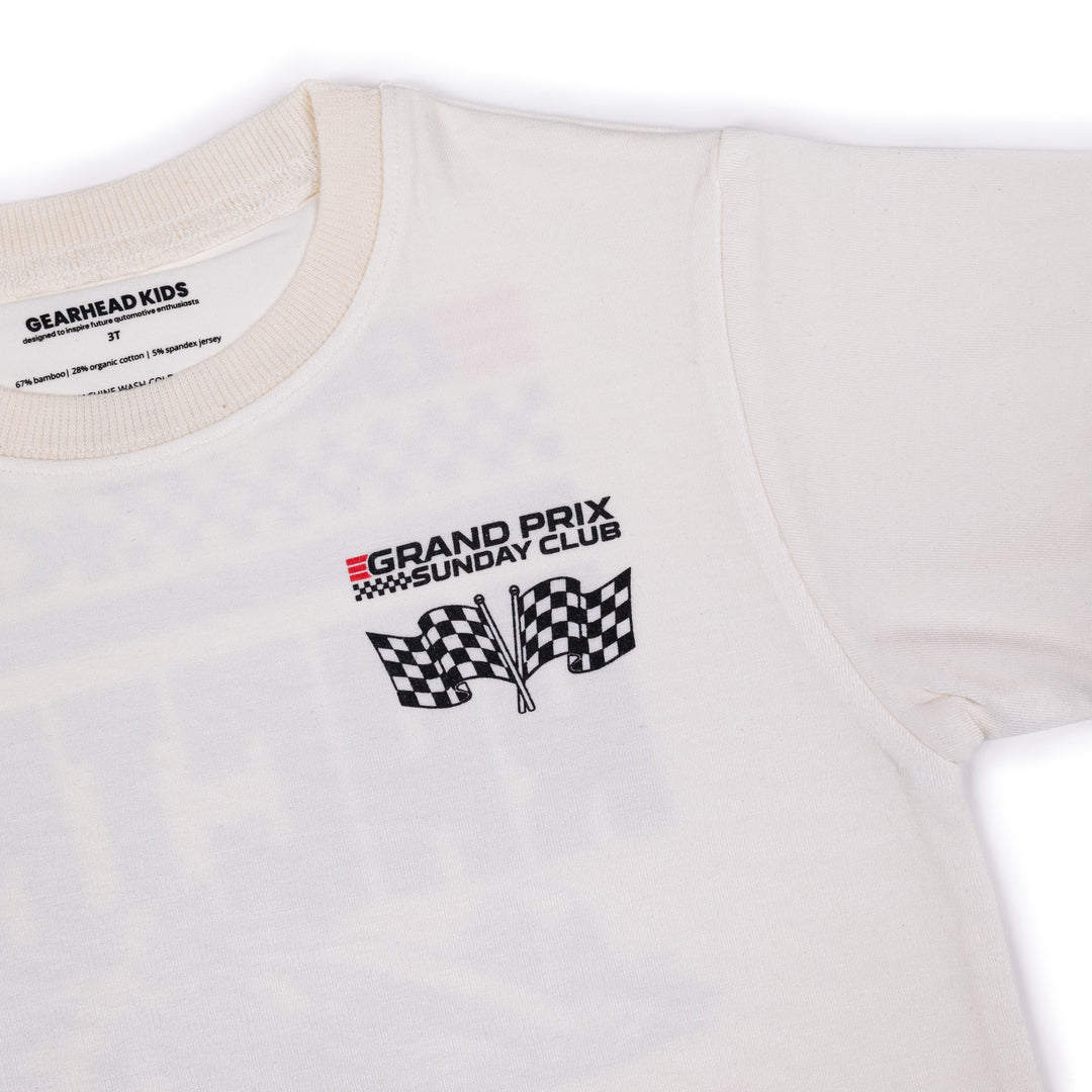 Closeup of the front of the Gearhead Kids Grand Prix Sunday Club t-shirt showing the clean chest logo with crossed checkered flags and red speed stripes on a white background.