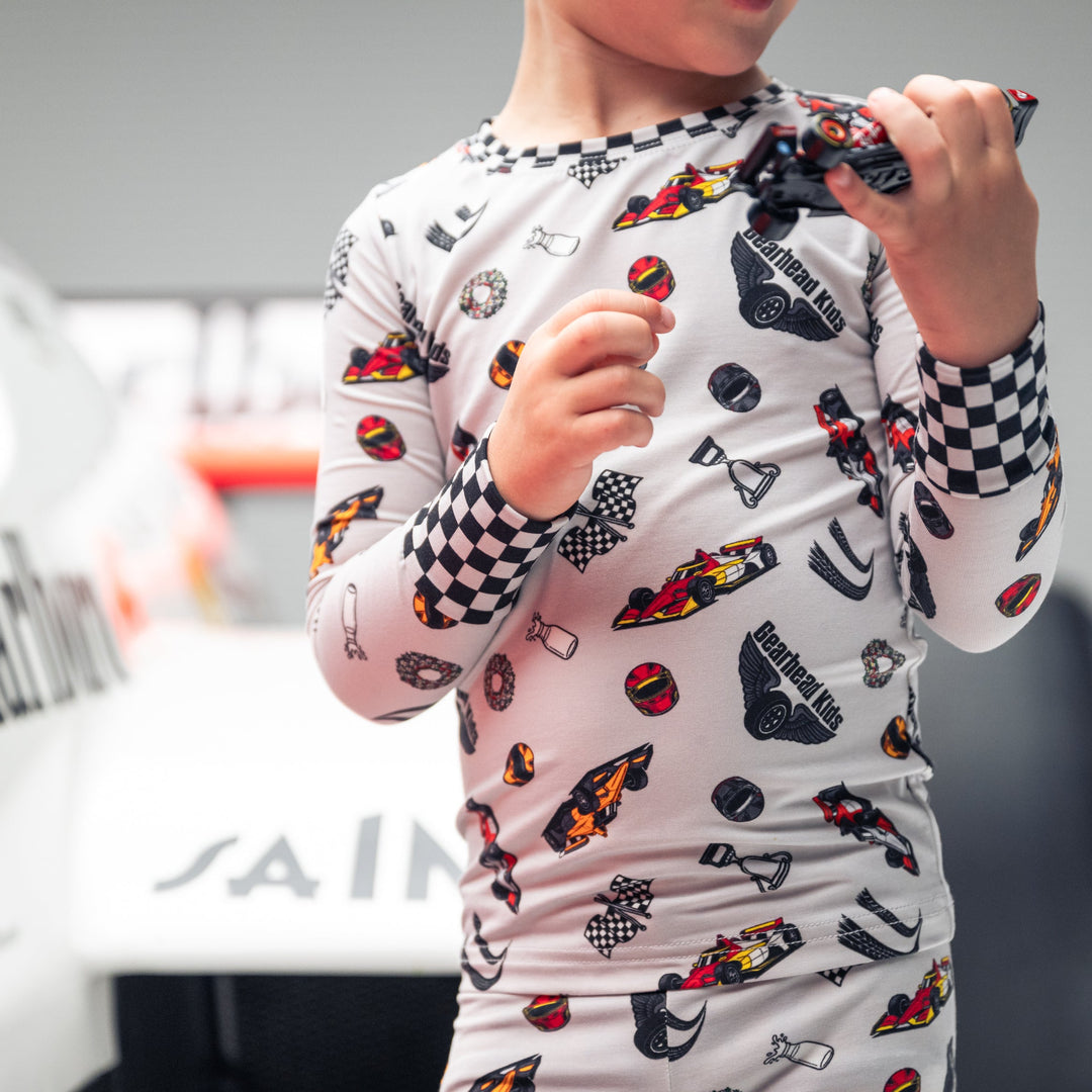 Little boy wearing bamboo pajamas featuring indy race cars, checkered flags, racing helmets, trophies, victory wreath and milk jug  |  Gearhead Kids
