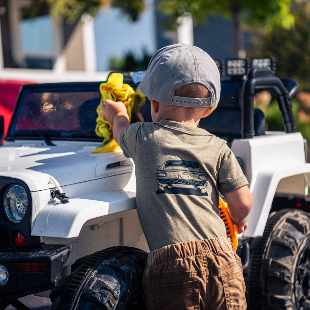 Little boy wearing a Lamborghini Miura onesie by Gearhead Kids washing his car.