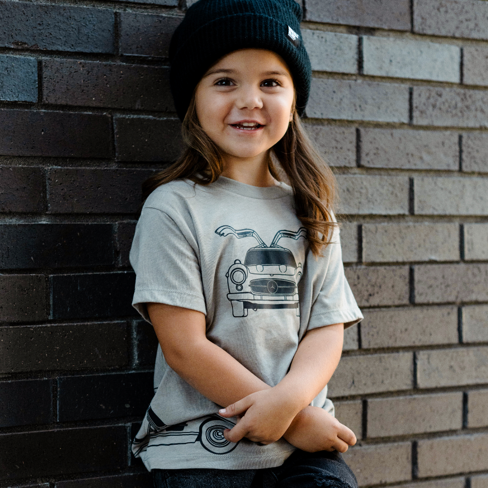 Girl wearing a Mercedes 300SL Gullwing Tee leaning against a brick wall | Gearhead Kids | Car-themed clothes for kIds
