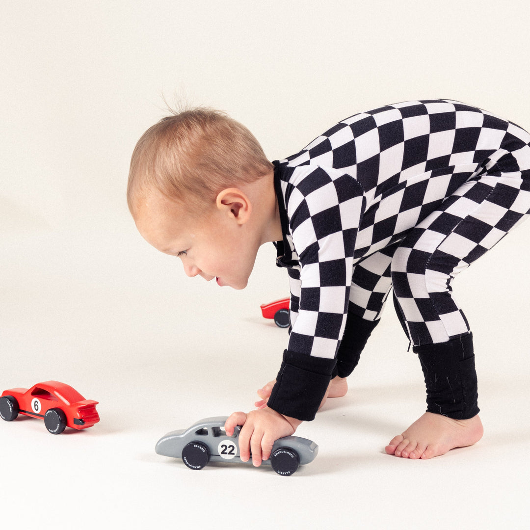 Toddler boy in black and white checkered bamboo pajamas playing with cars - Gearhead Kids