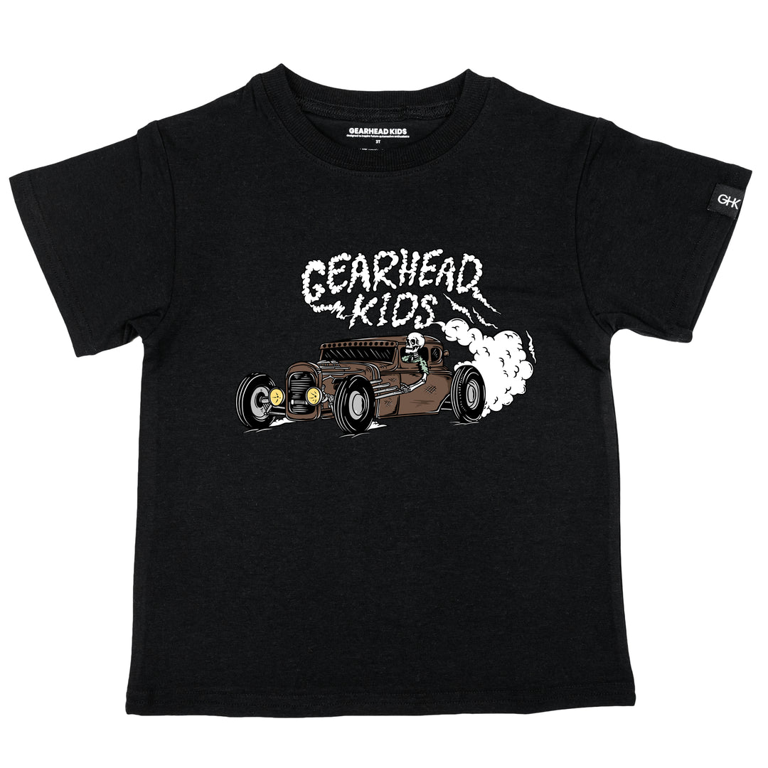 Kids black t-shirt featuring a skeleton driving a hot rod with Gearhead Kids tire smoke graphic from the Driven to the Bone collection